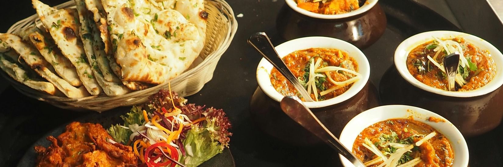 Different kinds of foods arranged on a table in different bowls and plates
