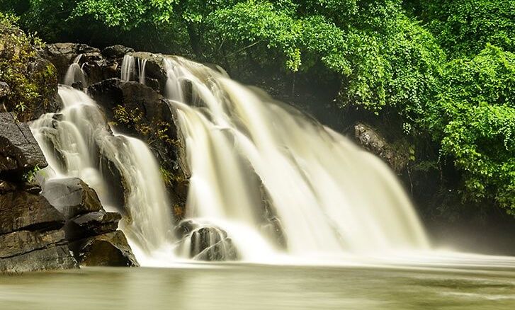 Coorg waterfall cascading over rocks into a serene pool.