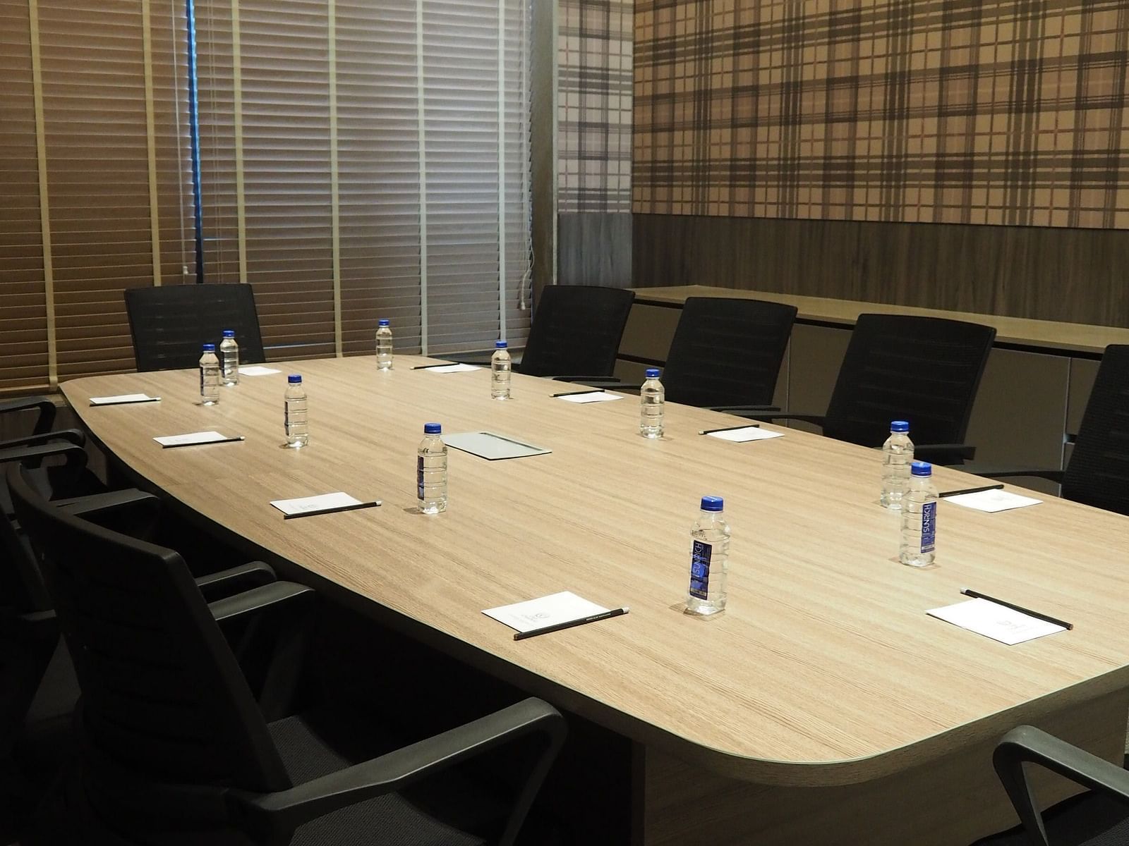 A long meeting table with chairs under a bright light in a room with striped walls - Club Charholi, Pune 