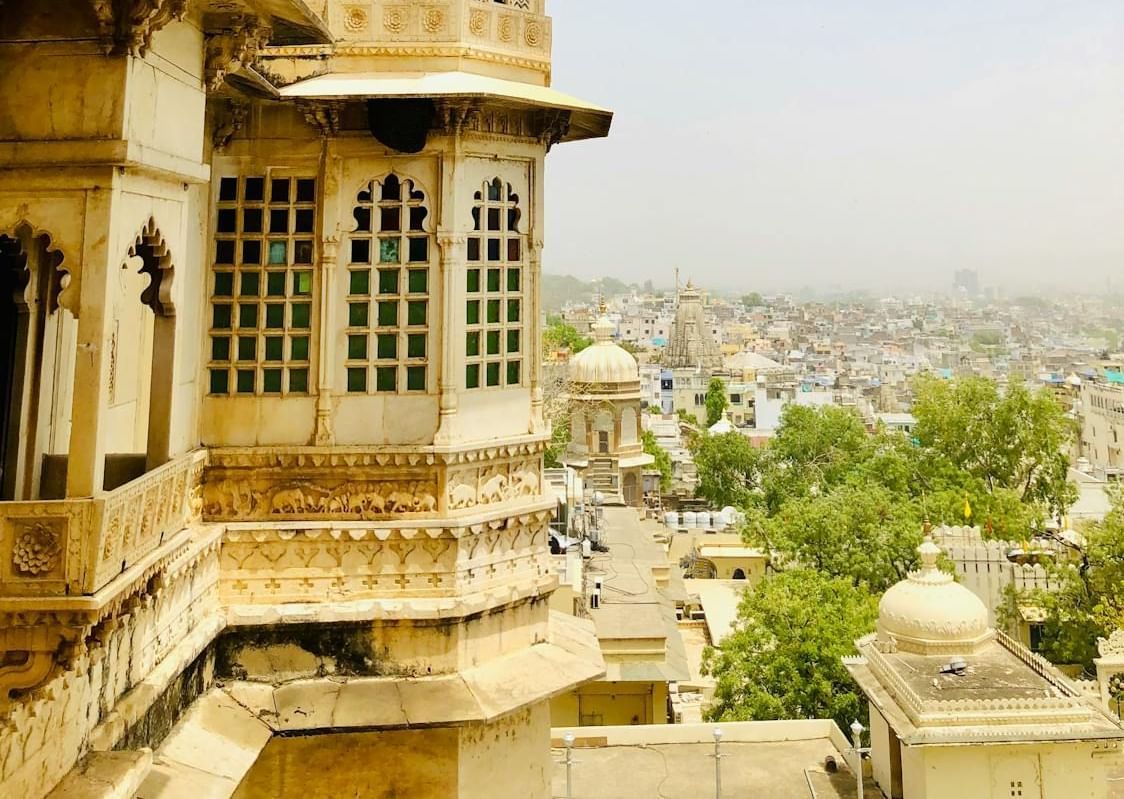 A portion of a palace with a domed tower overlooks a cityscape in the distance.
