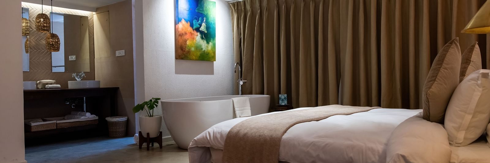 A spacious room with bed, bathtub, wall hanging and the washroom area at the Nepali Suite - The Nanee