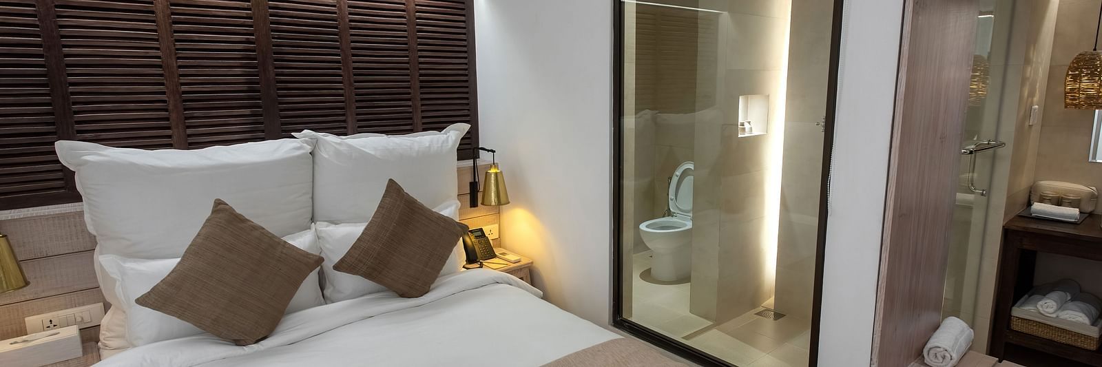 Standard room with a bed, bed side table, lamps and the washroom area - The Nanee
