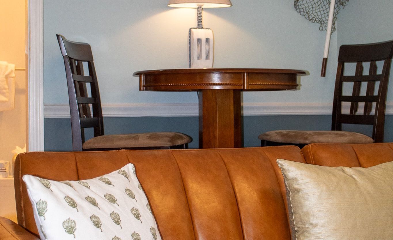 living area with tan leather sofa, nautical decor, fishing nets and vintage boat propeller at Hartstone Inn.