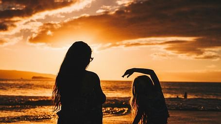 Two people sitting and chatting with a dramatic sunset behind them