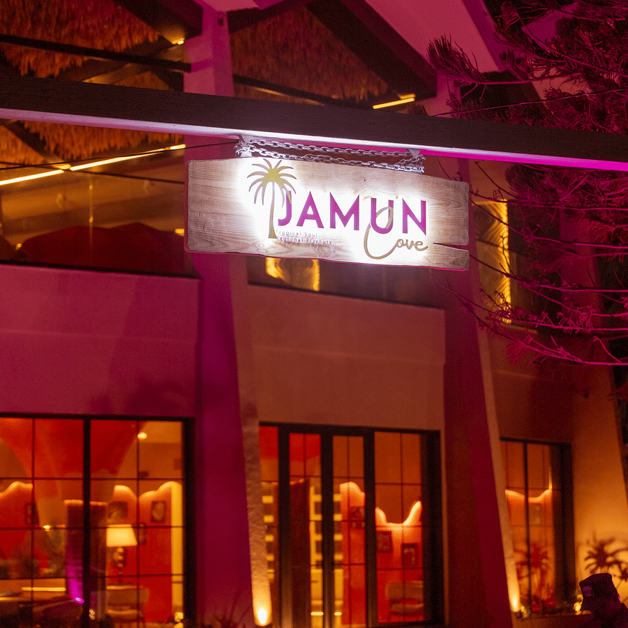 Exterior entrance of Jamun restaurant illuminated with purple lighting at night - Symphony Resorts