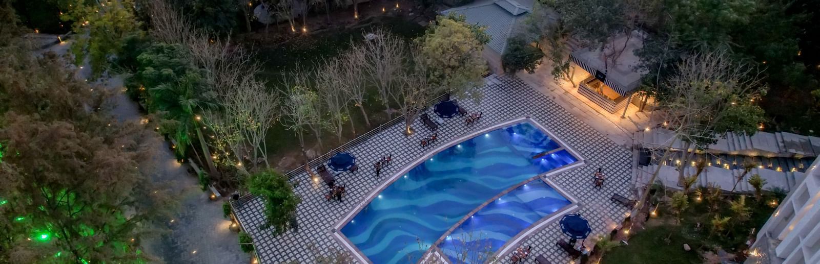 Aerial view of a swimming pool surroudned by trees at Essentia Luxury Resort and Spa, Udaipur