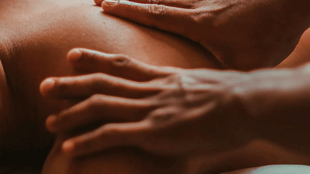A massage therapist massaging the back of  a person in the spa.