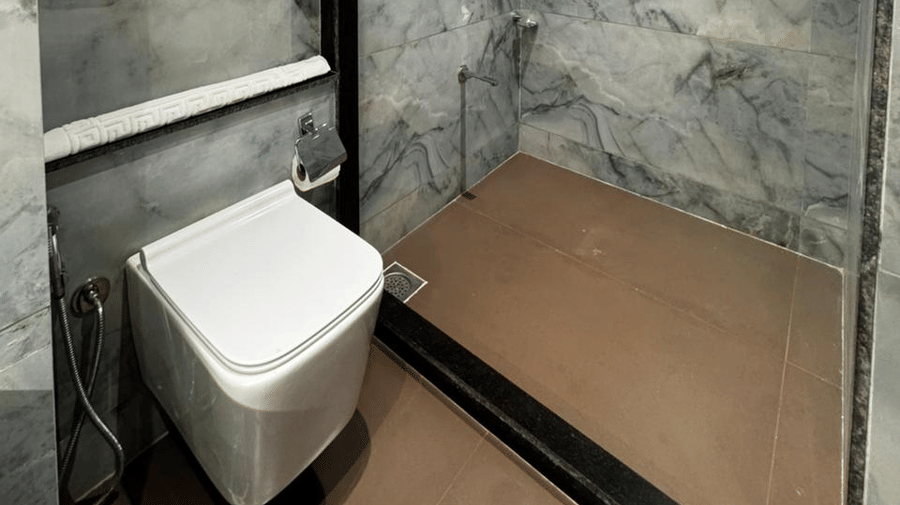 Elegant bathroom water closet with a shower area and wooden cabinetry - Lords Swastik Studio, Kodinar