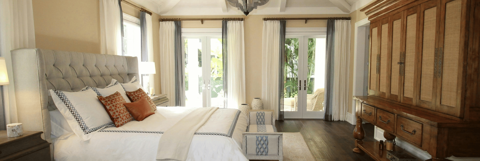Side view image of the bed with a chandelier hanging over the double bed.