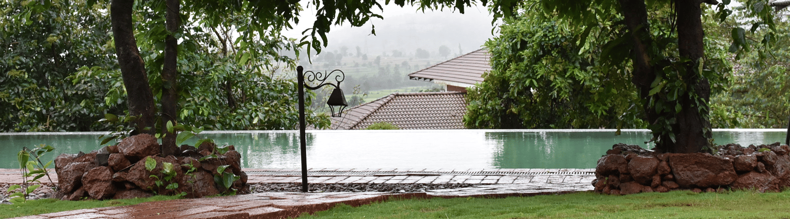 A tranquil outdoor space at Forest Escapes Koyna with a pond or water feature surrounded by lush greenery.