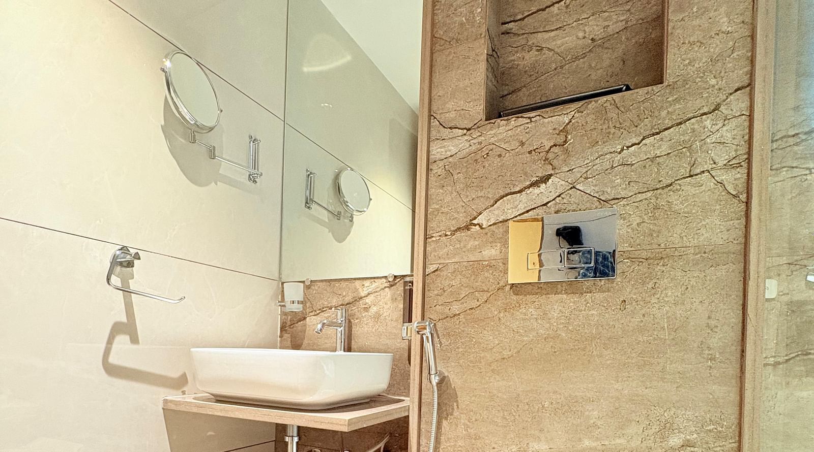 Bathroom featuring a wash basin, a mirror, and a toilet at Hotel Mumbai House, Vashi.