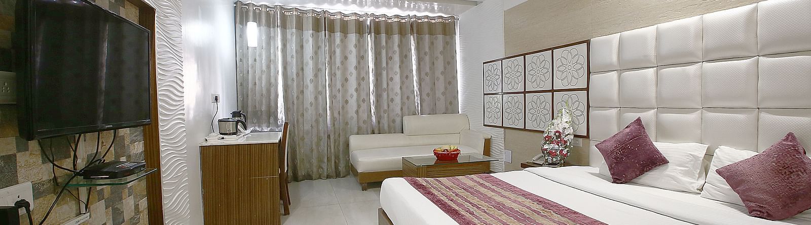 A sophisticated hotel room with plush bedding, a cosy seating area, and contemporary aesthetics - Hotel Emerald, Chandigarh