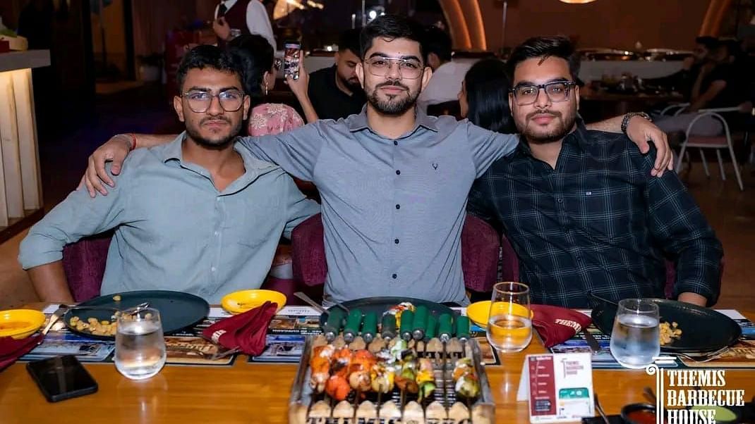 Guests posing for a photo with a spread of barbecue food in front at Themis Barbecue House, Ambala