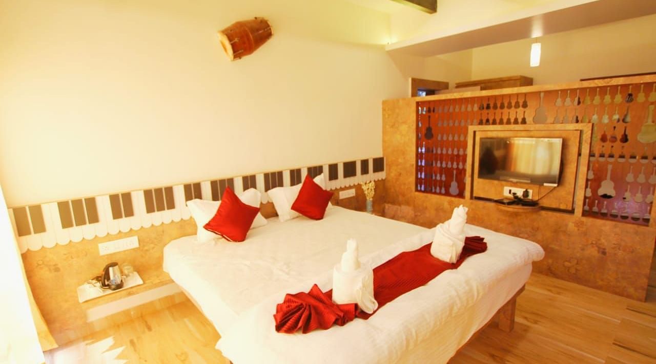 A diagonal view of the room featuring a spacious bed with towels folded in different shapes on it. There is a wooden table with a wall-mounted television at SeaFort Beach Resort