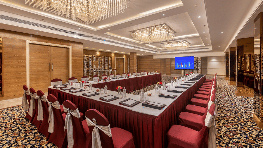 Elegant conference hall with red-draped chairs, chandeliers with a grand setup