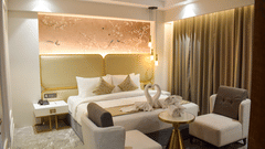 A king bed with dove towels, sofas in front of it in the suite at Tulip Inn, Shravasti