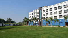 Side view of the lawn area with coconut trees and Tulip Inn, Shravasti in the background