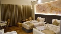 Twin beds with stydy table and sofa inside executive room at Tulip Inn, Shravasti