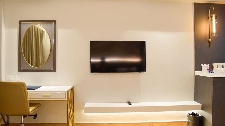 A wall mounted tv next to a mirror and study desk inside executive room at Tulip Inn, Shravasti