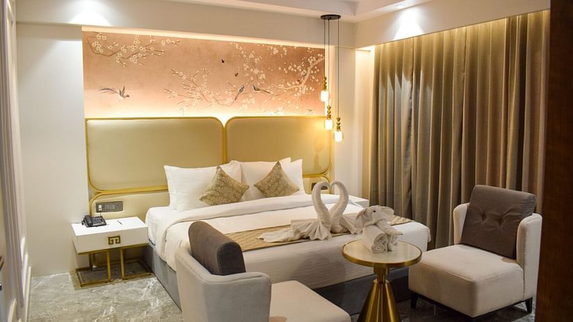 A king bed with dove towels, sofas in front of it in the suite at Tulip Inn, Shravasti