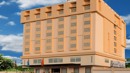 A large, multi-storey, beige hotel building with a red sign on the roof.