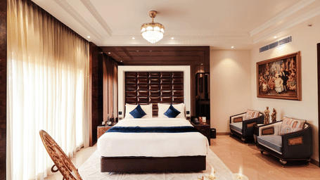 Spacious room at Hotel Hukam’s Lalit Mahal with modern furnishings, seating area, and natural light.