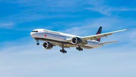 A large passenger airplane is captured in mid-air with its landing gear extended against a clear blue sky.