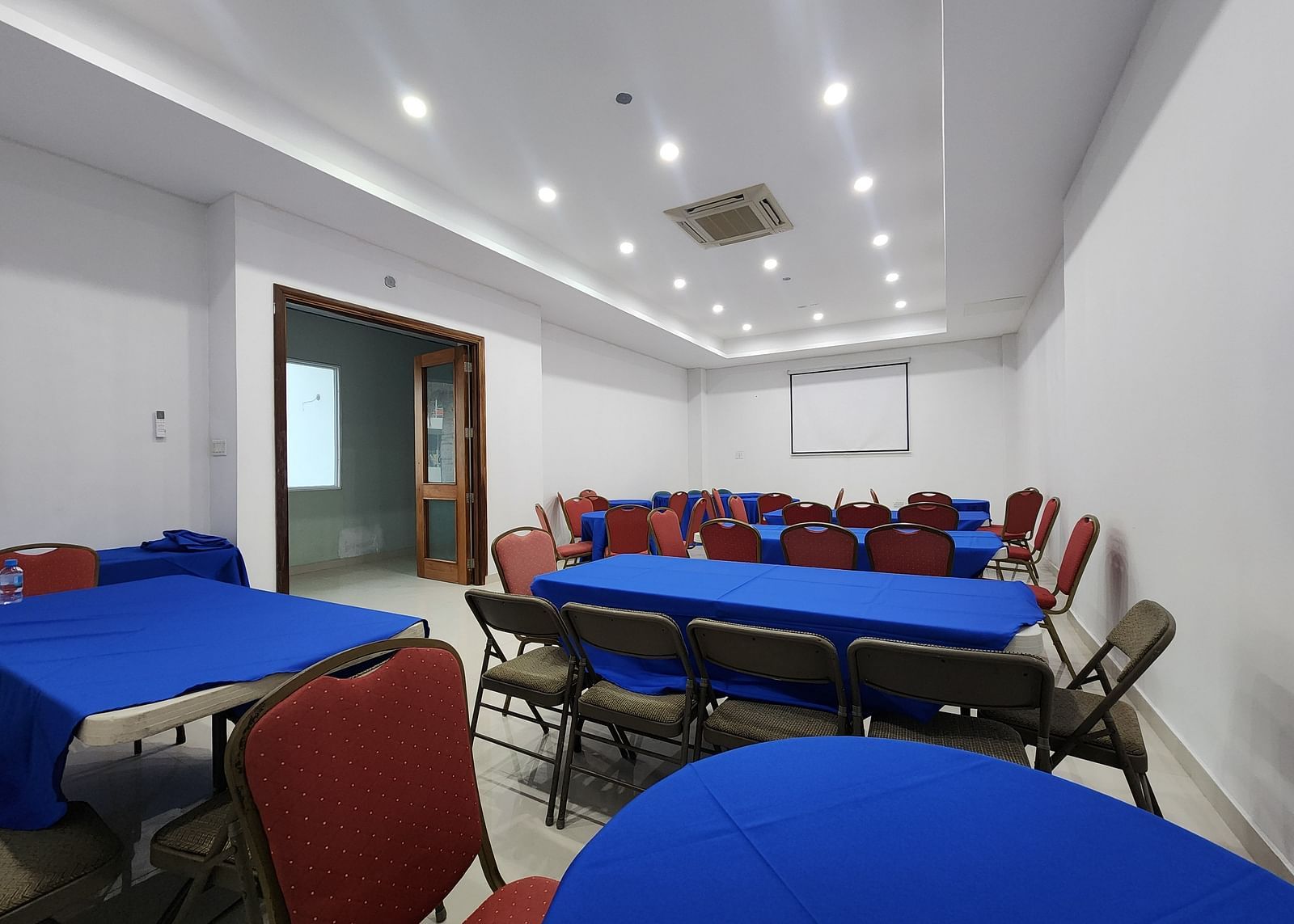 An image of Imagination  Lounge, our event hall in Montego Bay with chairs placed around long tables and a projector - Hotel 39, Jamaica (Montego Bay)