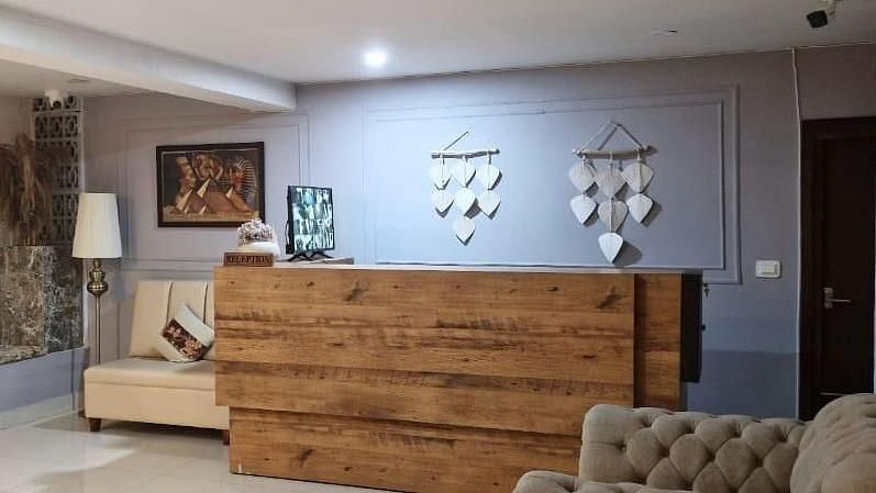 Lobby area with a wooden reception desk with two sofas in a modern waiting area. - VITS Kunjham Retreat, Gangtok