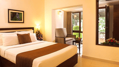 The superior room at Abad Hotels with a double bed with lamps on the side, a balcony opening, and wall-mounted landscape.