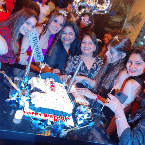 Group of friends celebrating a birthday with a themed cake at Central Courtyard Boutique Hotel.