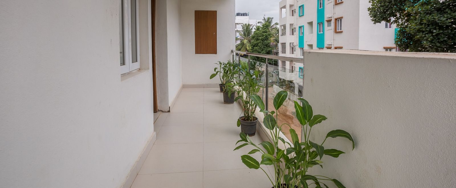A bright balcony with potted plants and a view of a light-coloured building exterior - Sanctum Suites BEL Road, Bangalore