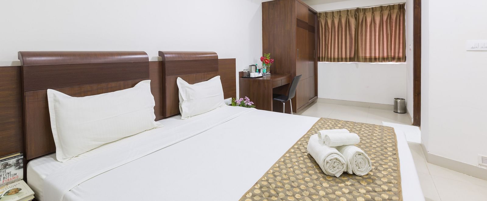 A room with a double bed, a patterned bed runner, a work and a chair, and a wardrobe - Sanctum Suites BEL Road, Bangalore
