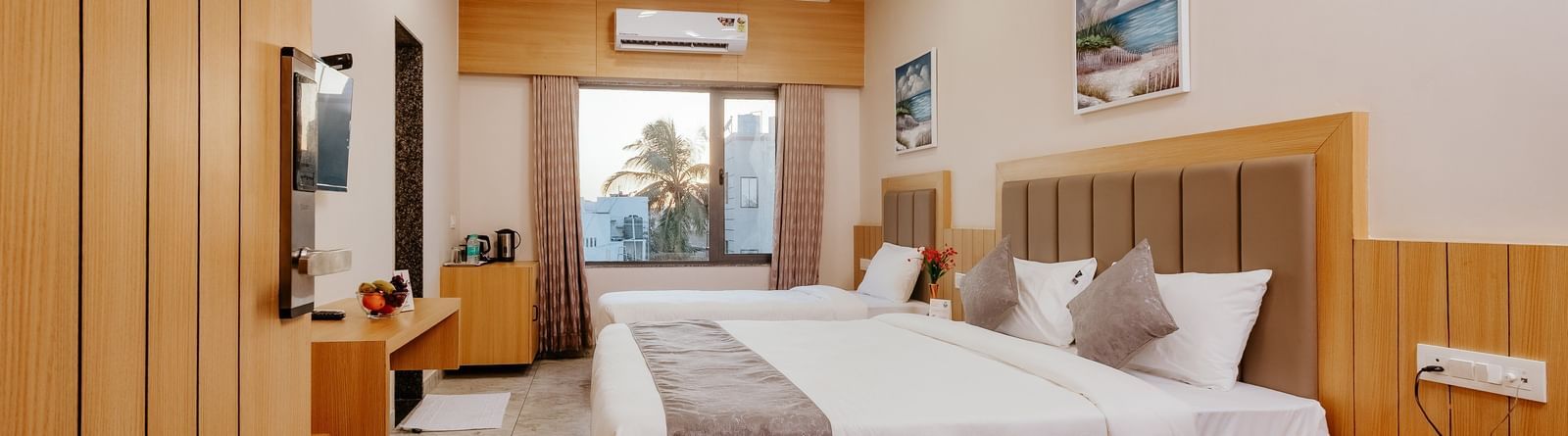 Spacious Pride Room at Daksh The Grand Gowardhan, Dwarka, with multiple beds, modern decor, and a view from the window at the far end.