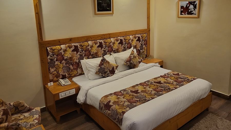 A bedroom with wooden accents, floral-patterned headboards, and warm lighting at Dagshai Manor Kasauli - Inde Hotels.