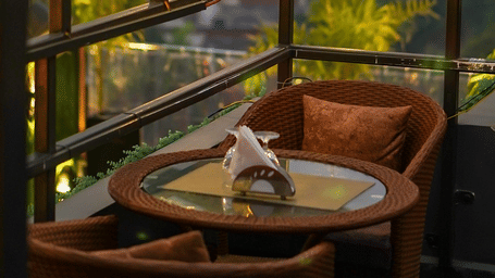 Two chairs facing each other on a terrace with warm lights besides it on a late evening.