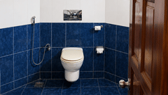 Bathroom with blue tiled walls and a clean, well-lit toilet area at Chariot Beach Resorts, offering a comfortable and hygienic space.