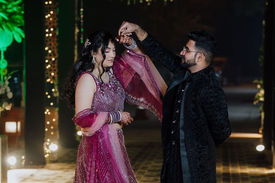 Bride and groom sharing a romantic moment under hanging golden lights and chandeliers.