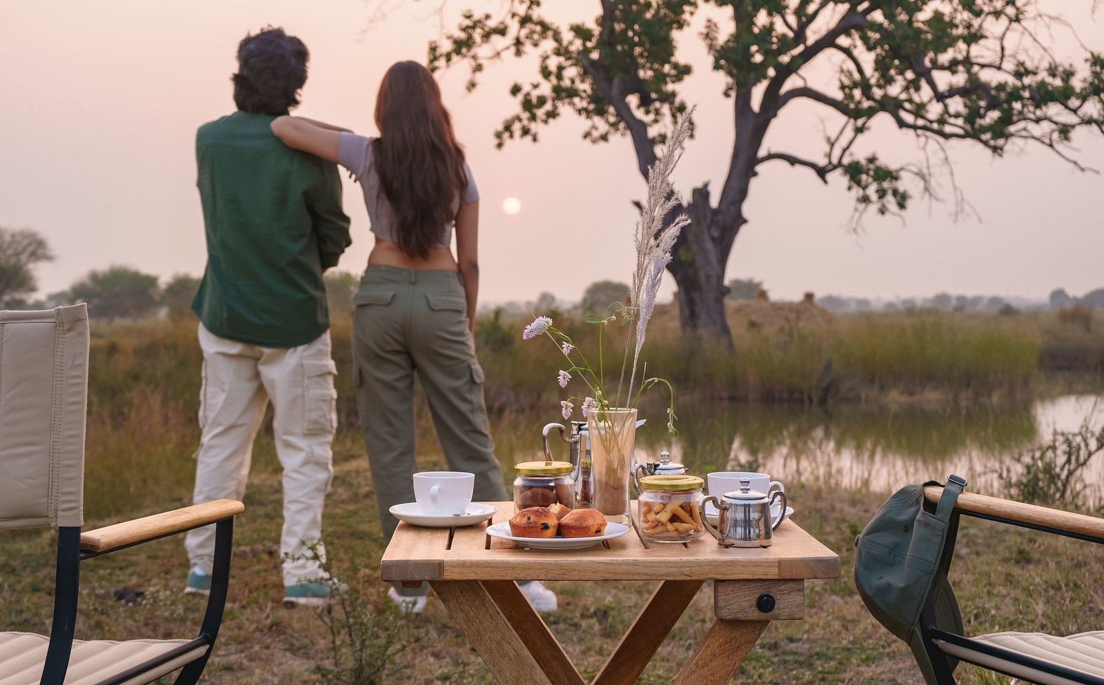Couple watching a sunset with a dining setup at Trees N Tigers, Tadoba.