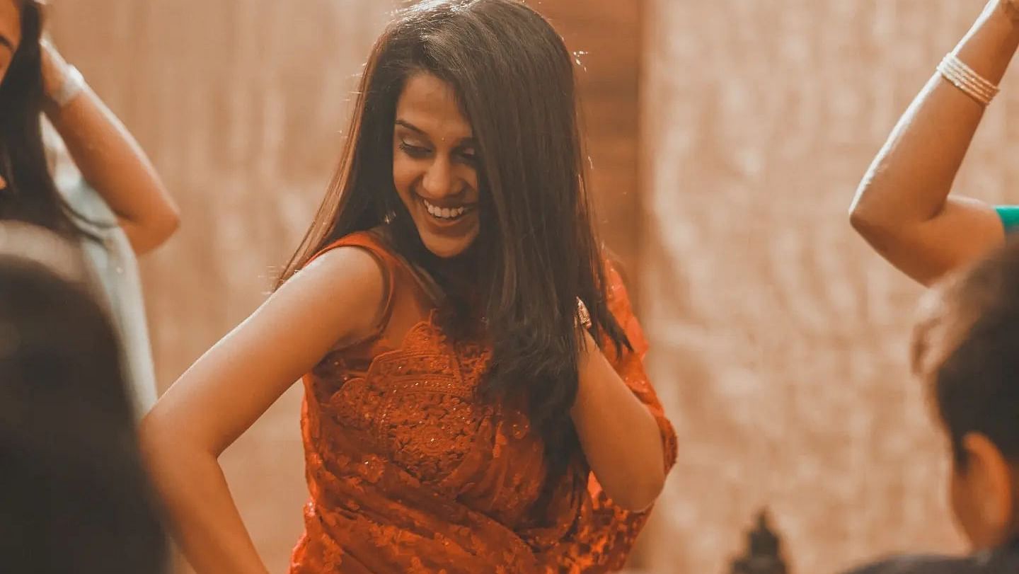 Woman smiling and dancing during an indoor event at Mansha Regency, Port Blair.