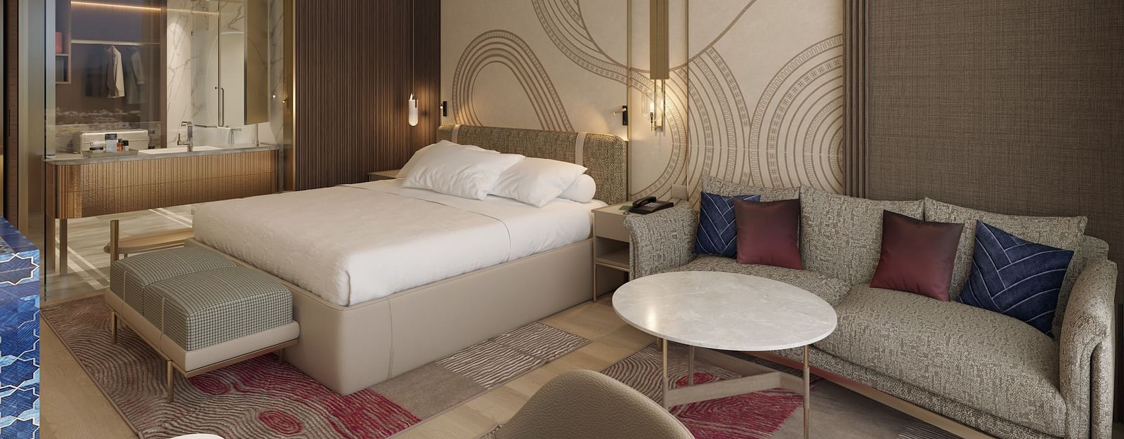 A side view of a modern hotel room with a large bed, seating area featuring a sofa and round table, and a vanity mirror in the background at Merlis Hotel, Coimbatore