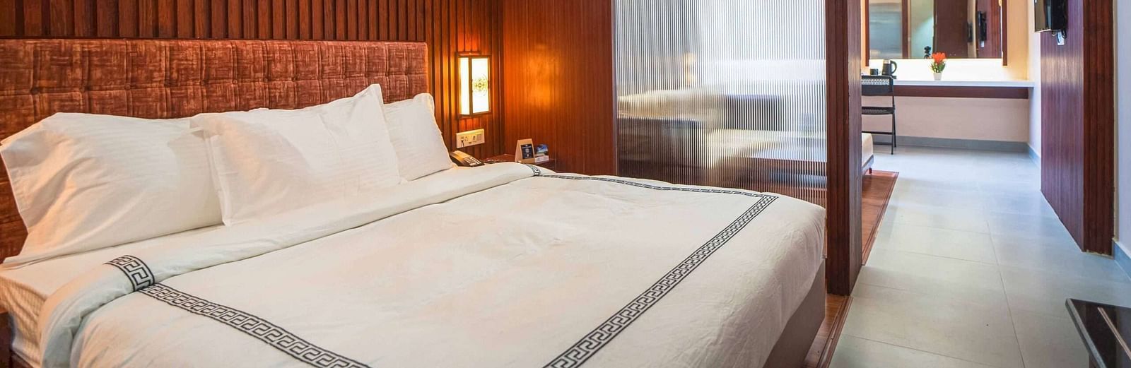 A stylish bedroom at Mansha Palace features a comfortable bed and a partial view into an adjacent area with a desk.
