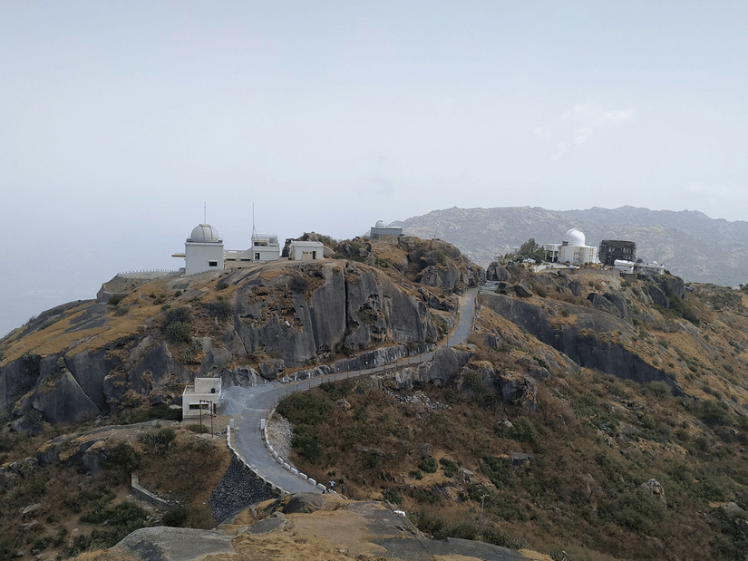 Drone view of a hilltop temple complex connected by pathways through lush greenery.