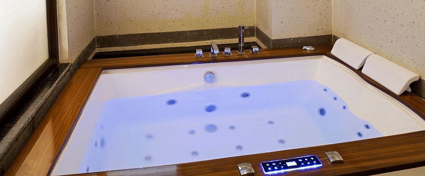 A Jacuzzi tub with blue lighting in the bathroom of the Suite at Regenta Inn DLS.