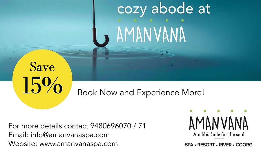 Orange umbrella in rain with water droplets against blue sky, advertising Amanvana Spa Resort, Coorgs monsoon experience with 15% discount offer