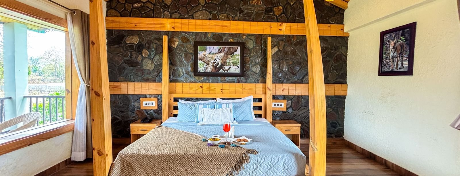 Elegant bedroom with four-poster bed and rustic decor at Corbett Nirvana Resort.