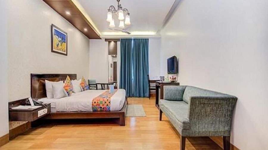 Room at Rockland Hotel, Panchsheel Enclave, New Delhi, featuring stylish lighting, wooden flooring, a cosy seating area, and contemporary decor.
