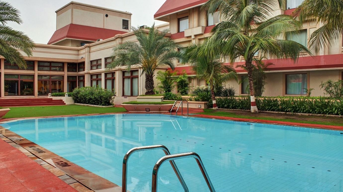 View of a pool with a building in the background, surrounded by trees for added decor.