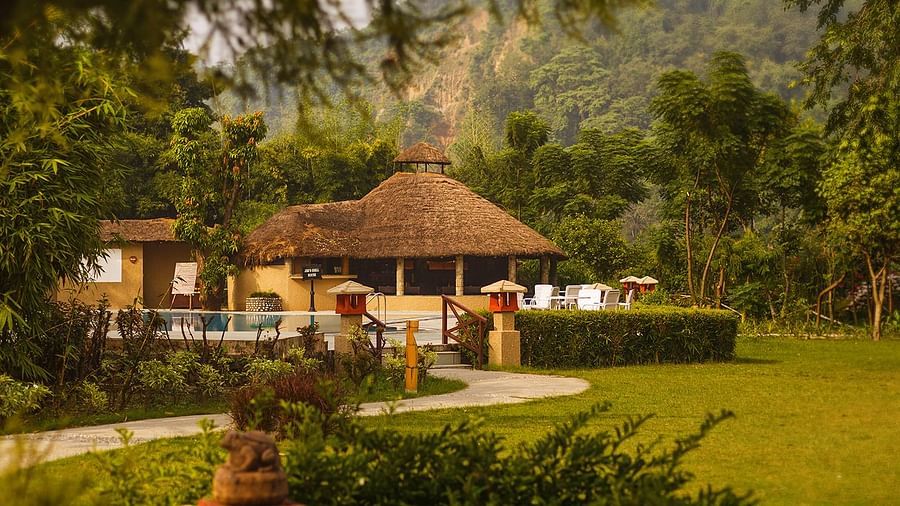 An image of a hut amidst the garden and  behind it there is a seating area with chairs and table- The Riverview Retreat, Corbett