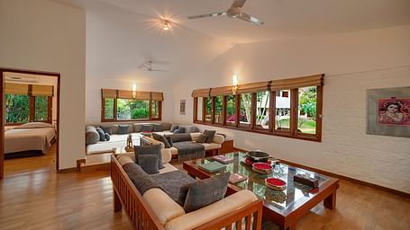 A living room with a couch, armchairs, a coffee table, and large windows - Shreyas Retreat